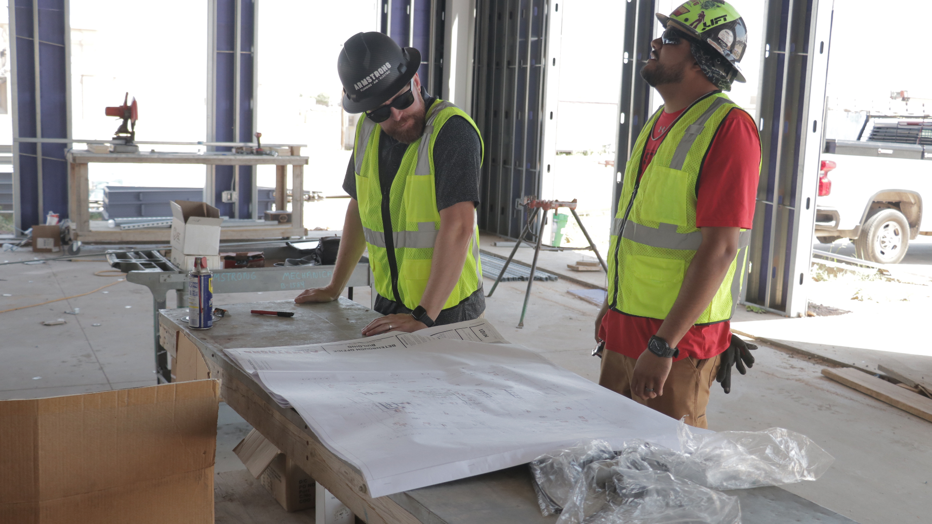 Armstrong construction team reviewing blueprints on commercial job site